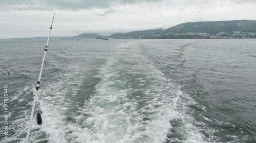 A view from a floating fishing boat in Avacha Bay of the Pacific Ocean during cloudy, choppy weather. The city is in the background