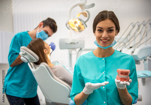 Obraz na płótnie Dental assistant showing braces model in clinic.