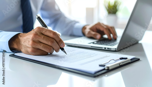 Businessman Writing on Clipboard and Typing on Laptop in Office.