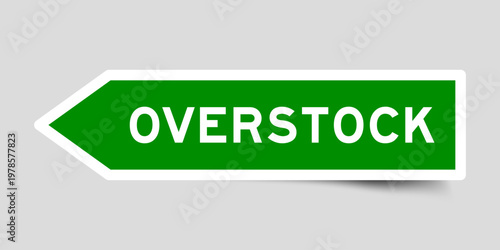 Green color arrow shape sticker label with word overstock on gray background