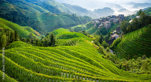 Lush green rice terraces and traditional ethnic minority village houses in Longji, Guilin, China.