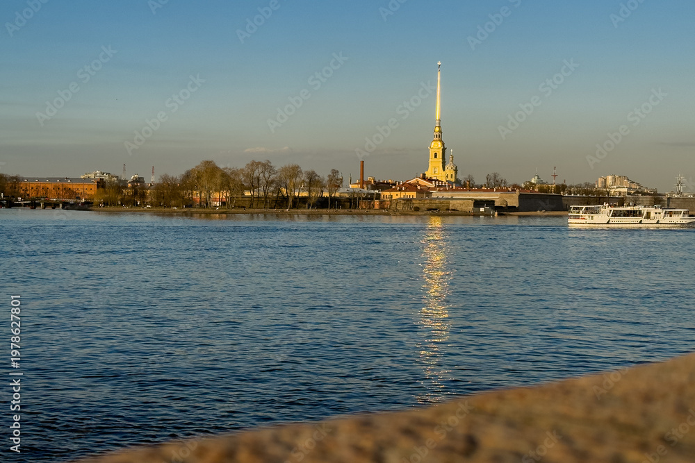 Fototapeta premium Peter and Paul Fortress across Neva River at sunset with boat, Saint Petersburg