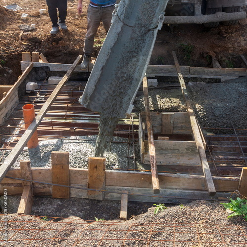 A migrant worker fills a septic tank with concrete on a summer day.