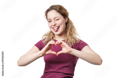 Fotografie A woman on a white background shows her tongue and a heart with her hands