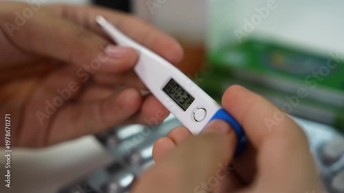 Close-up of hands holding a digital thermometer showing a fever reading, medical checkup concept with blurred background.