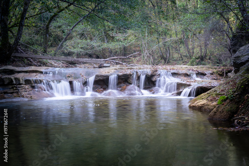 small lake with waterfalls in a forest in autumn