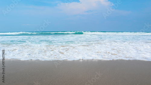 Tableau sur toile Pristine beach where vibrant turquoise ocean waves break into a thick layer of white sea foam