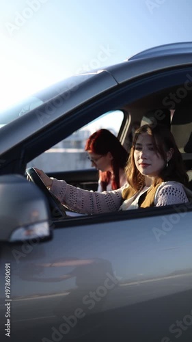 Vertical screen young woman driving car during lesson while instructor sits beside giving directions and observing her actions building confidence and control behind the wheel