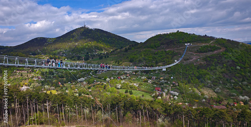 Modern suspension bridge (Hungarian National Unity Bridge)connecting hills above Sátoraljaújhely, Hungary, with scenic valley, forests and spring landscape under dramatic clouds.