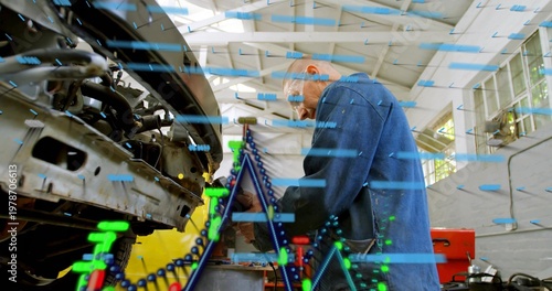 Leaning mechanic in blue coat repairing engine using wrench at garage, overlays visible, copy space
