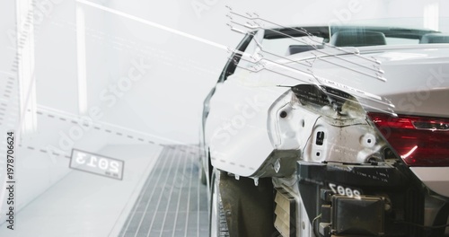 Showing white sedan rear-right quarter exposing panel and removed bumper in paint booth, copy space