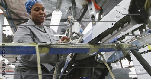 Adjusting operator in gray jacket, blue-scarf at line, using white control panel with taped rail