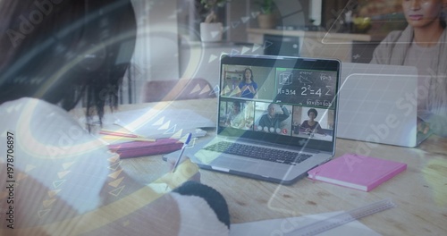 Writing left teen white-sweater dark-cuffed, studying at wooden table with laptop and pink notebook