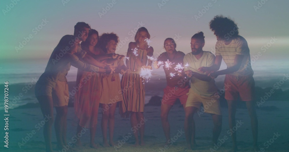 Fototapeta premium Gathering 8 adults in summer wear laughing, holding sparklers barefoot on sand at dusk, gentle surf