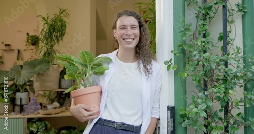 Non-binary adult holding terracotta pot, leaning in doorway and smiling as camera moving closer