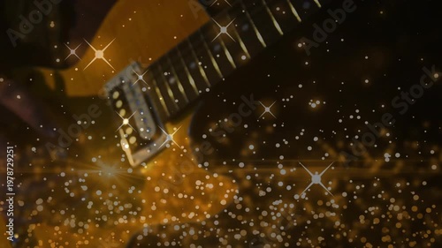Plucking gold electric guitar, hands in dark sleeves moving on fretboard in dim studio, star bokeh