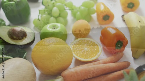 Vertical video: Panning camera revealing halved avocado and orange on white table, showing spread