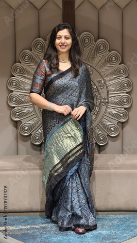 Elegant Indian woman in ajrak print saree with lagdi patta border posing indoors, showcasing traditional ethnic fashion and graceful festive style against ornate decor backdrop.