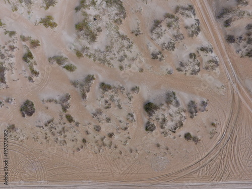 Aerial view of desert terrain with tire tracks and sparse vegetation