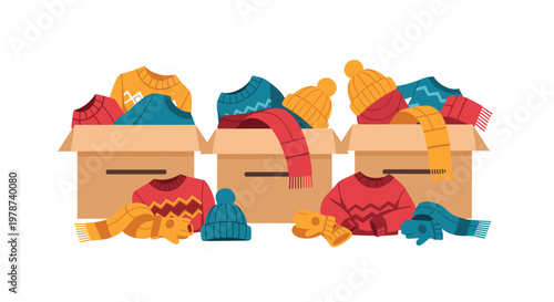 Three cardboard boxes overflow with cozy winter clothing items including knitted sweaters, wool scarves, warm hats, and gloves scattered on a clean floor.