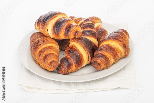 Freshly baked croissants on plate close up on white background