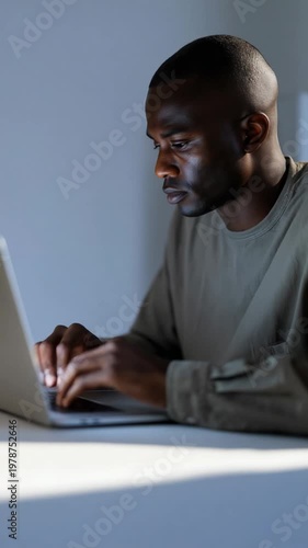 Man works on laptop in a bright room during the day while sitting at a table