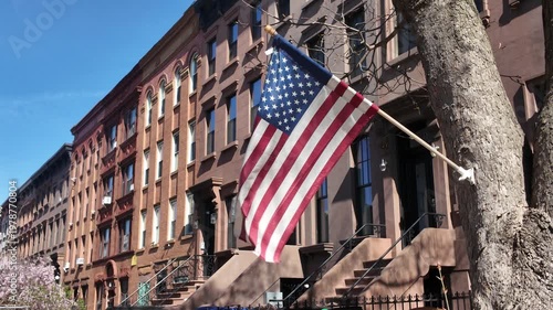 alt American flag flapping in front of Brooklyn brownstone houses