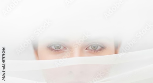 Intense Eyes Peeking from Under White Sheets in a Minimalist Setting.
