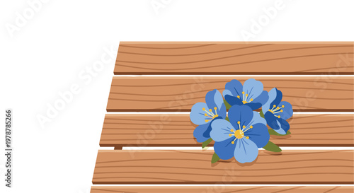 Vibrant blue forget-me-not flowers with bright yellow centers rest gracefully upon a warm brown slatted wooden table surface against a clean white backdrop.