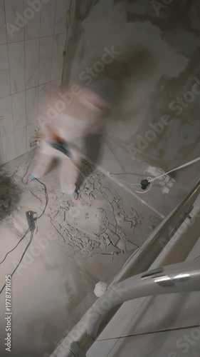Worker breaking bathroom floor during renovation