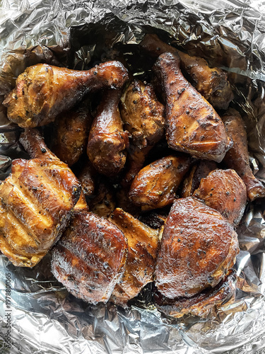 Delicious smoked chicken parts on metal foil after grilling in a BBQ smoker outdoors