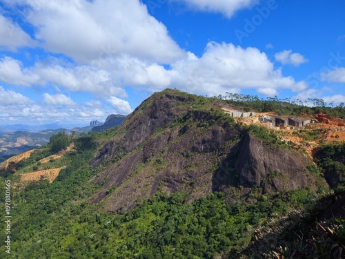 Large stone mountain landscape featuring an active open pit quarry extraction site under blue sky