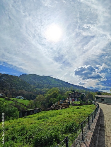 Traditional stone house situated in the green valley below the impressive mountains on a sunny day