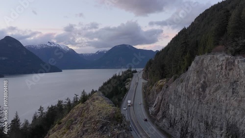 Scenic Highway Along Howe Sound: Cars Driving Through Majestic British Columbia Mountains at Dusk