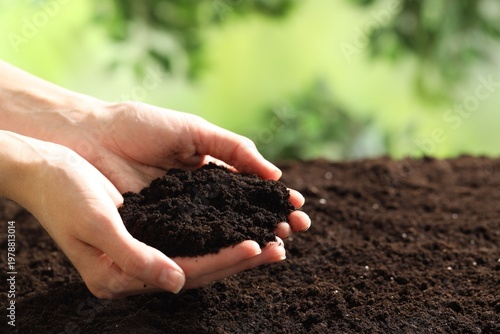 Woman with fresh soil on blurred background, closeup