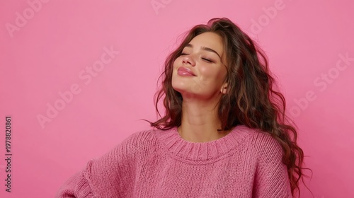 Smiling Person With Curly Hair Poses Against a Pink Background in Casual Clot...