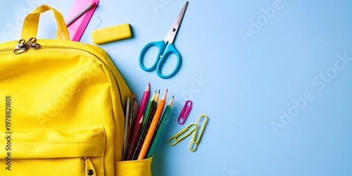 School Supplies Are Arranged Next to a Yellow Backpack on a Blue Surface Duri...