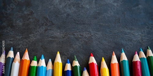 Colorful Pencils Arranged in a Row on a Dark Surface With Even Spacing
