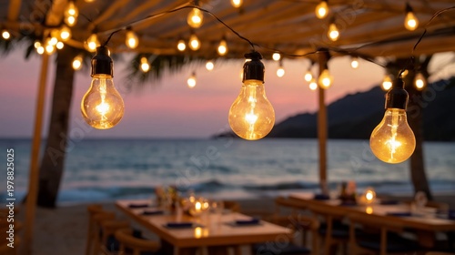 Strings of Lights Hang Over Tables by the Beach at Sunset With Ocean View in ...