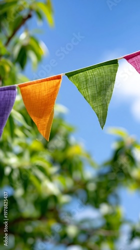 Colorful Flags Sway in the Breeze Under Bright Blue Sky and Green Tree Leaves
