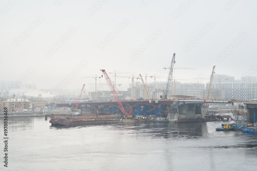 Fototapeta premium Foggy bridge construction with cranes and site engineer oversight