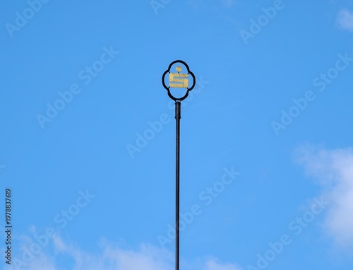 Foto Single black streetlight tower against bright blue daytime sky with soft clouds