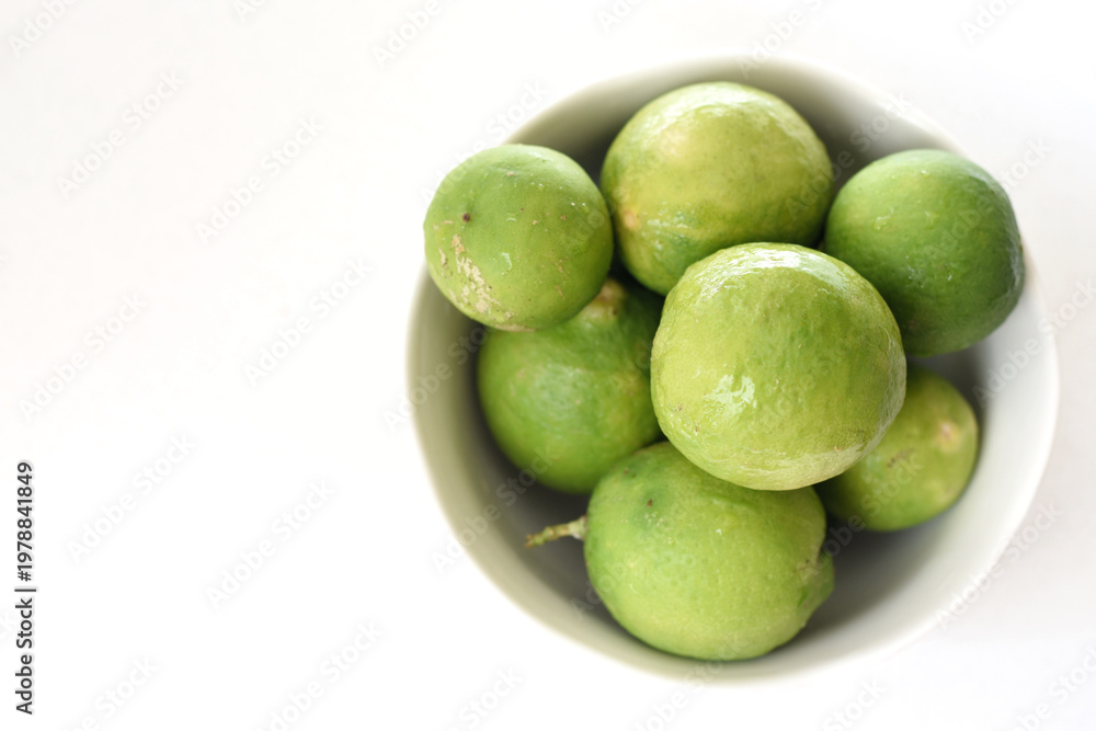 Obraz premium Top view of fresh green limes arranged on a clean white table, creating a bright and minimal citrus background. Ideal for concepts of freshness, healthy lifestyle, natural ingredients, summer drinks