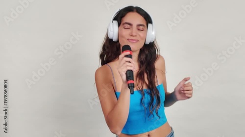 Young happy woman singing karaoke and dancing on white background