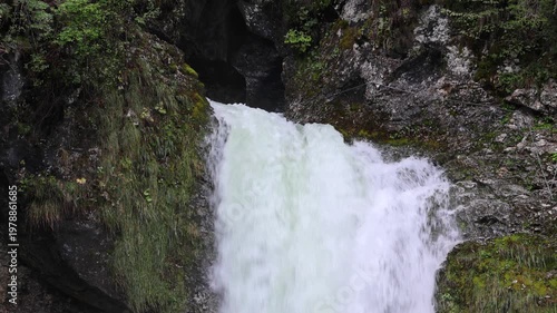 beautiful scenic small waterfall in forest next to farm river and bike trail in bohinj slovenia europe (stunning landscape julian alps alpine mountains scenery) trees woods hiking hike path trail