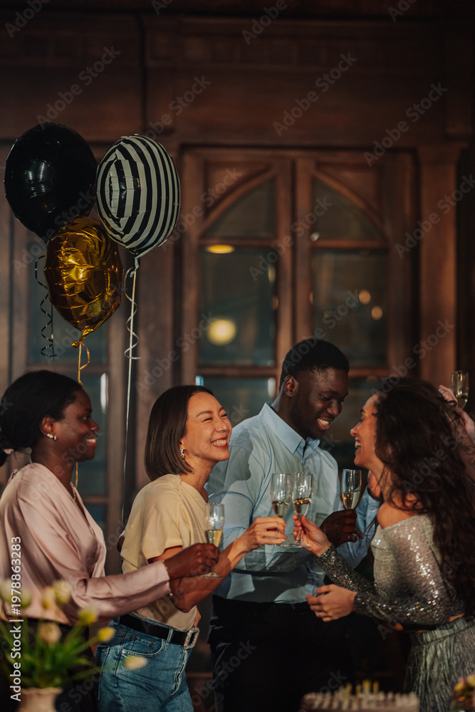 Fototapeta premium Diverse friends celebrating a party, toasting with champagne glasses and laughing. Joyful social gathering with balloons