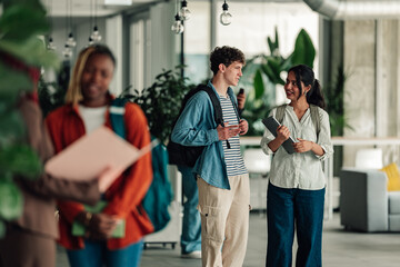 Diverse students walking and communicating in modern campus building, discussing education and future goals