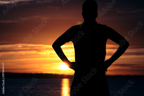silhouette of a man near a lake during sunset