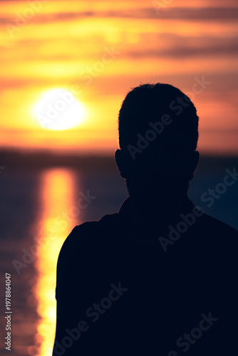 silhouette of a man near a lake during sunset