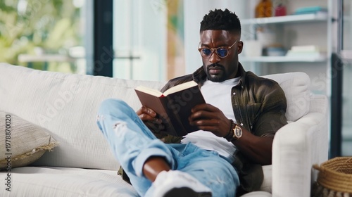 Older Man Reads Book While Sitting on Sofa in Cozy Living Room During Afternoon